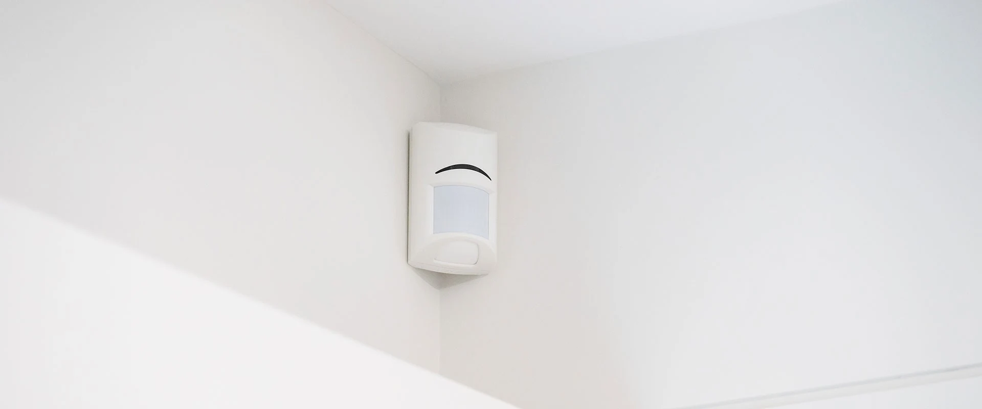 A motion detector mounted high in the corner of a room