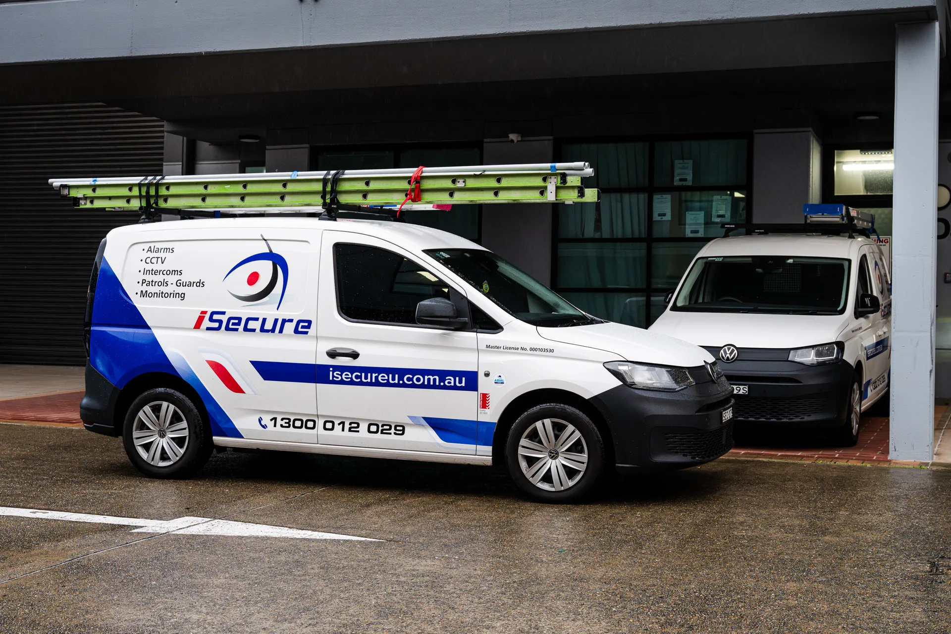 An iSecure van loaded with ladders outside a commercial building