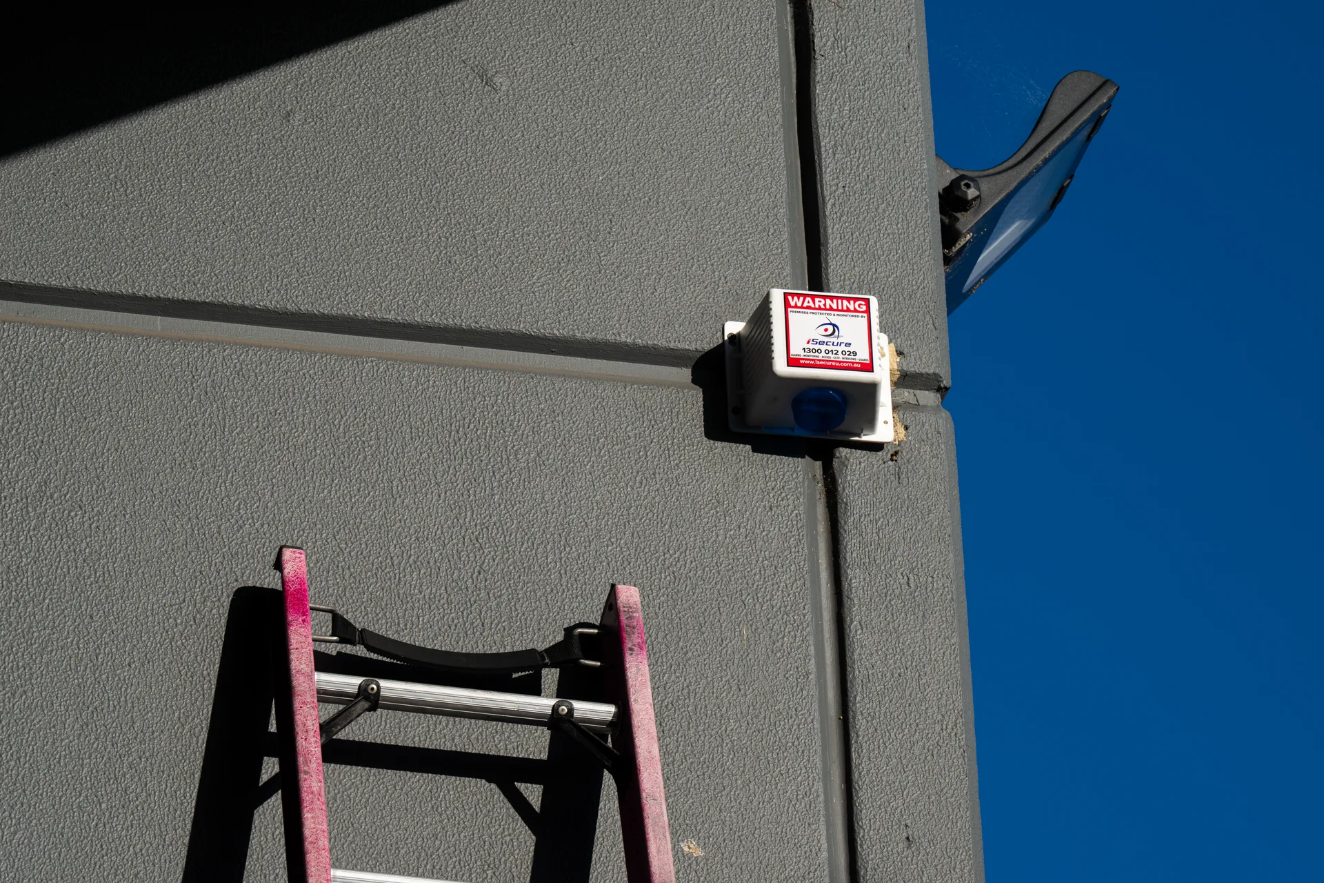 An iSecure monitored alarm siren mounted high on a building wall
