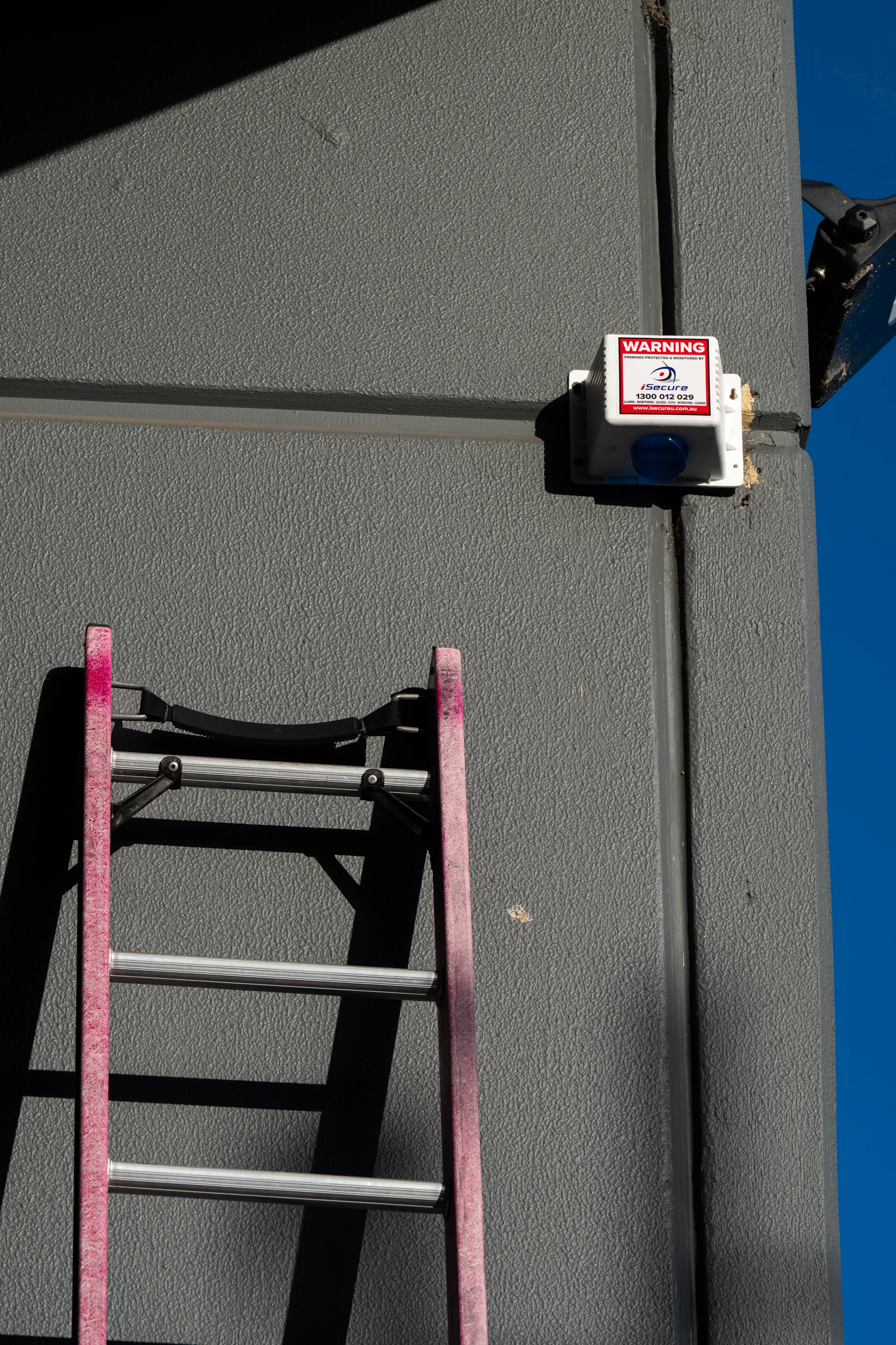 An iSecure monitored siren box high on a wall