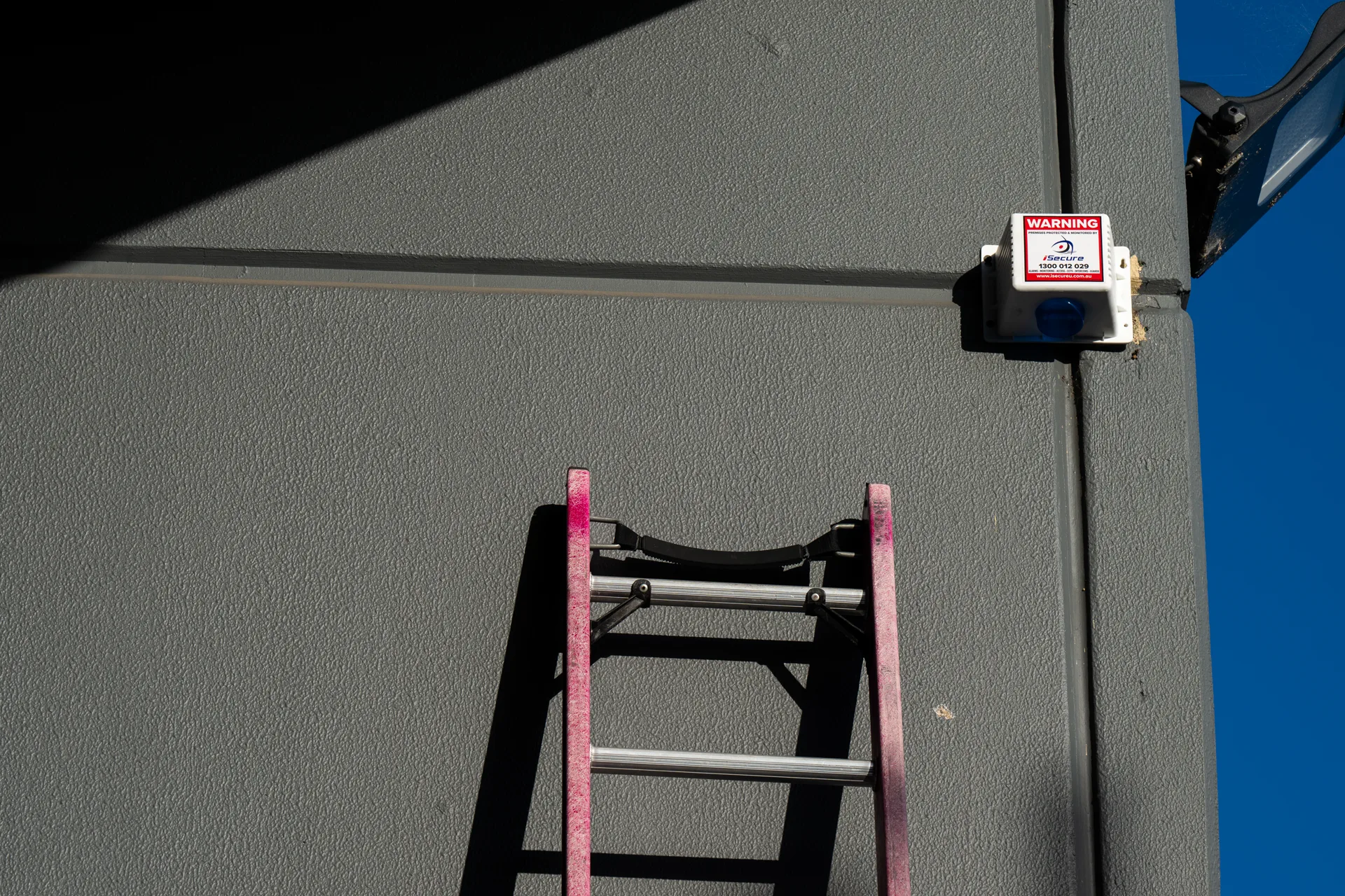 An iSecure monitored siren being installed high on a building wall