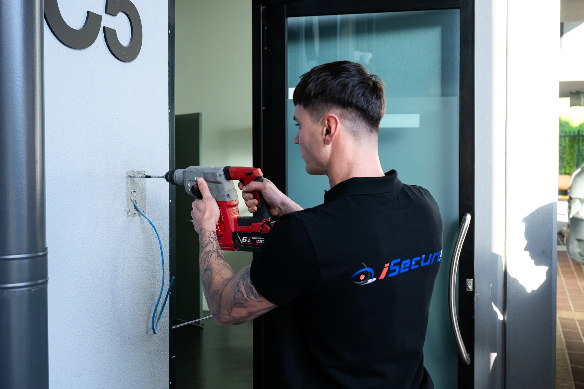 An iSecure technician drilling beside an entry door