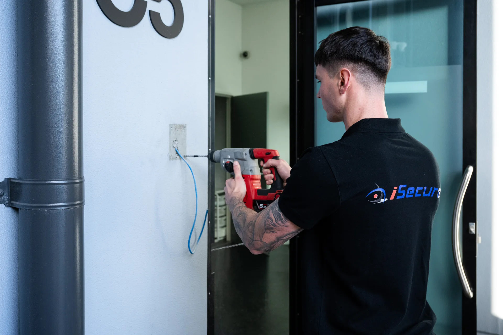 An iSecure technician installing a reader beside a commercial entry door