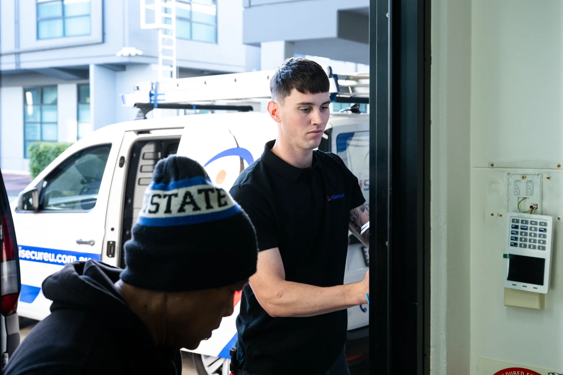 An iSecure technician at an entry door with a keypad panel