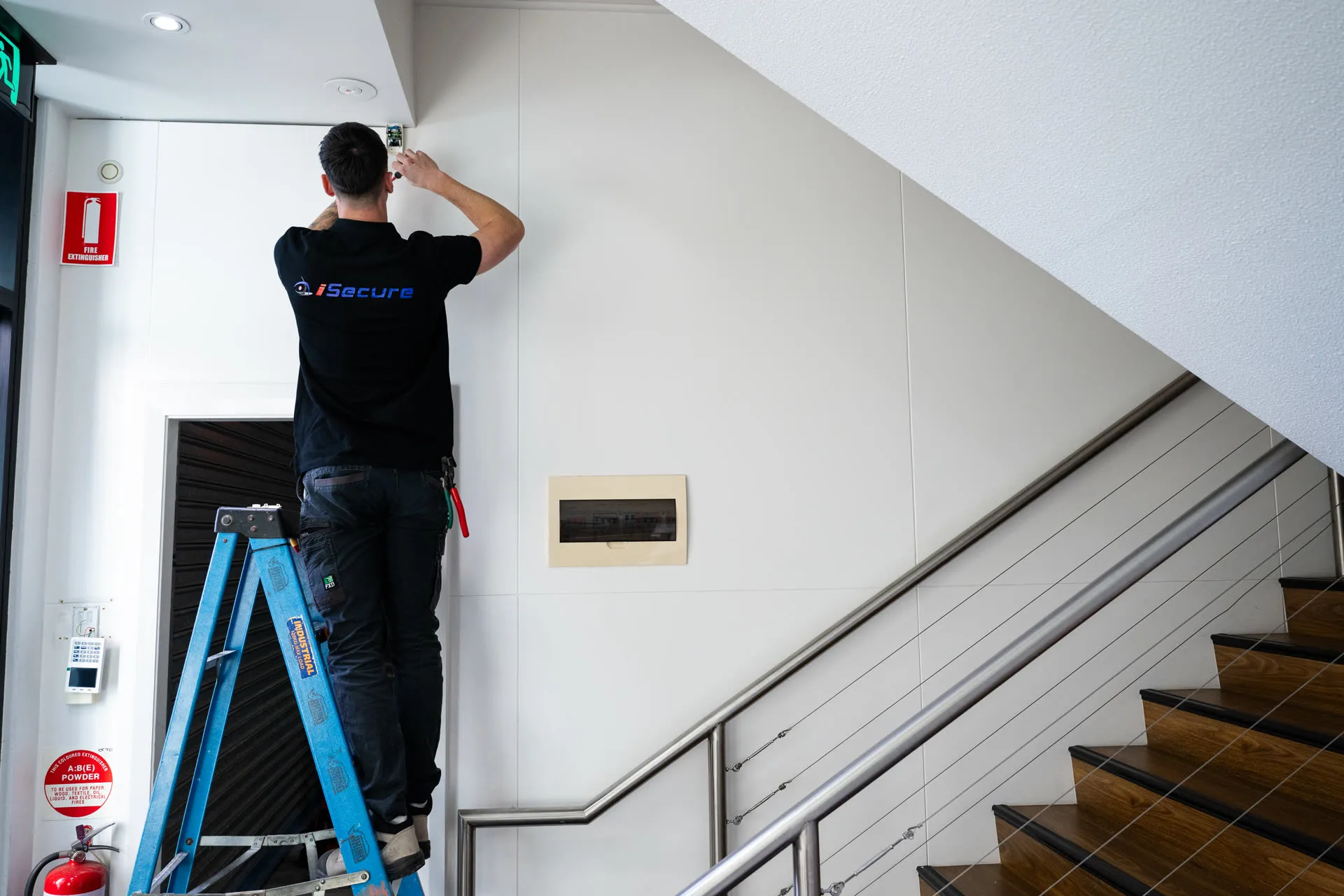 Technician wiring a device above a stairwell