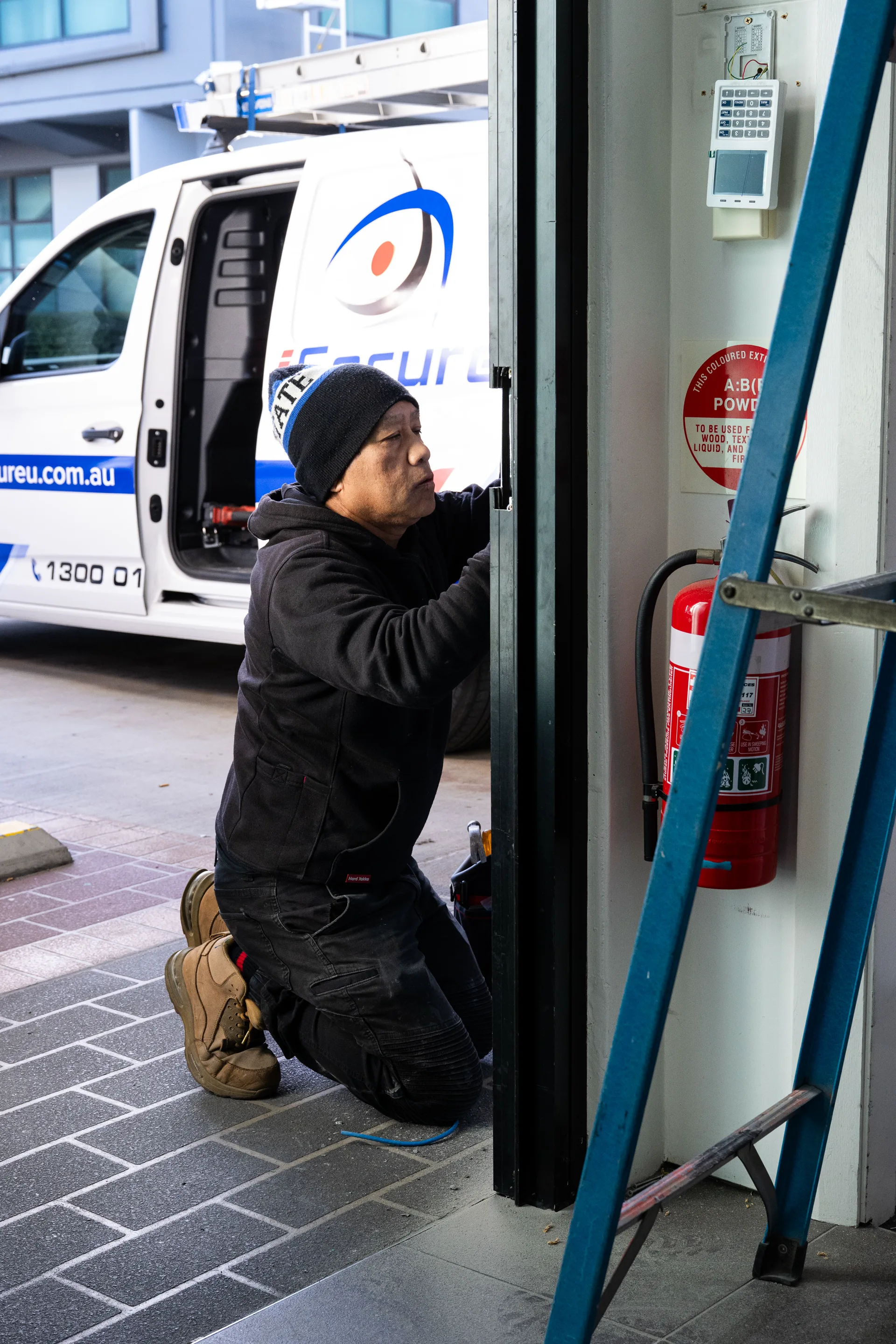 An iSecure technician fitting hardware at an entry door