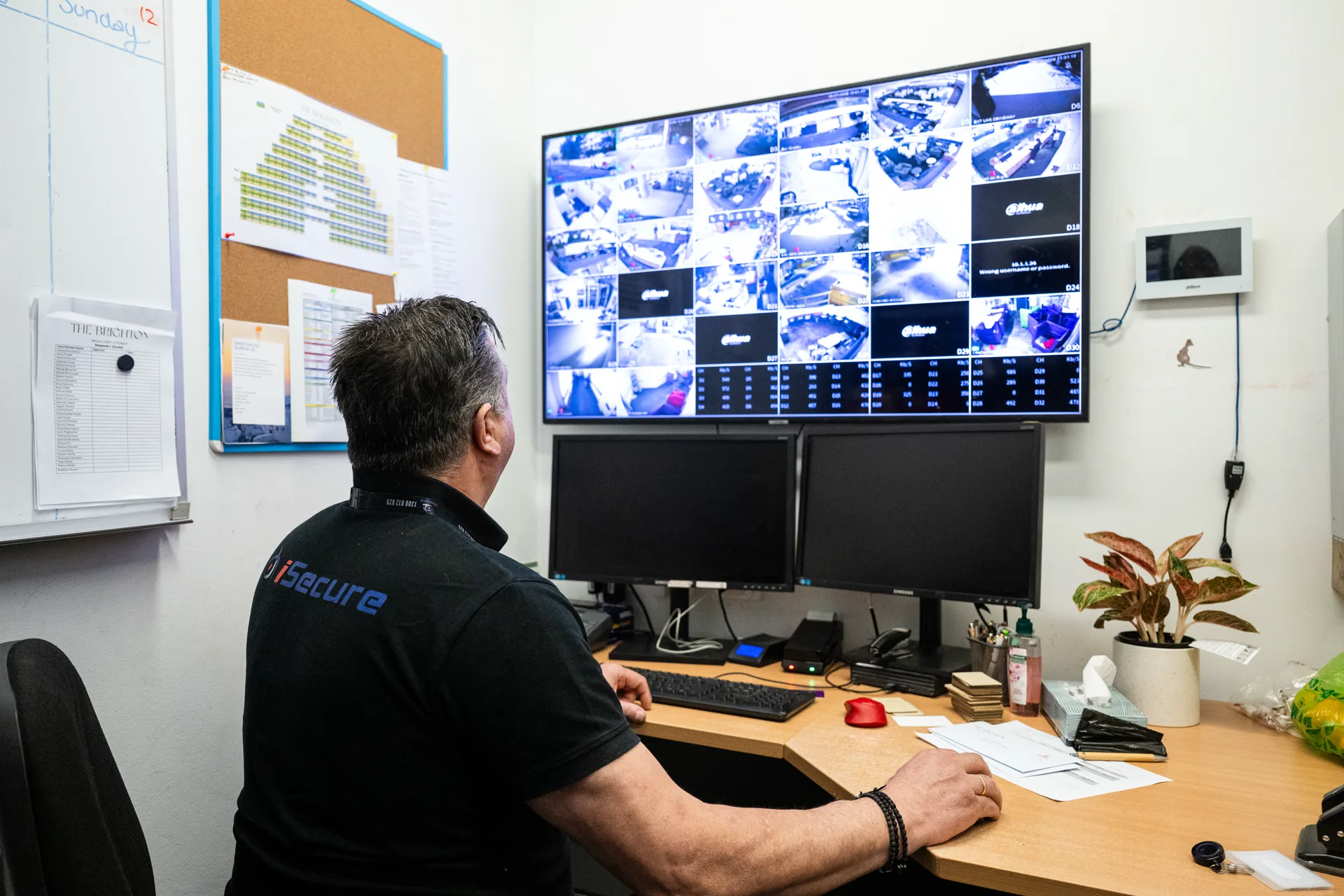 An iSecure operator watching a wall of live camera feeds at a desk