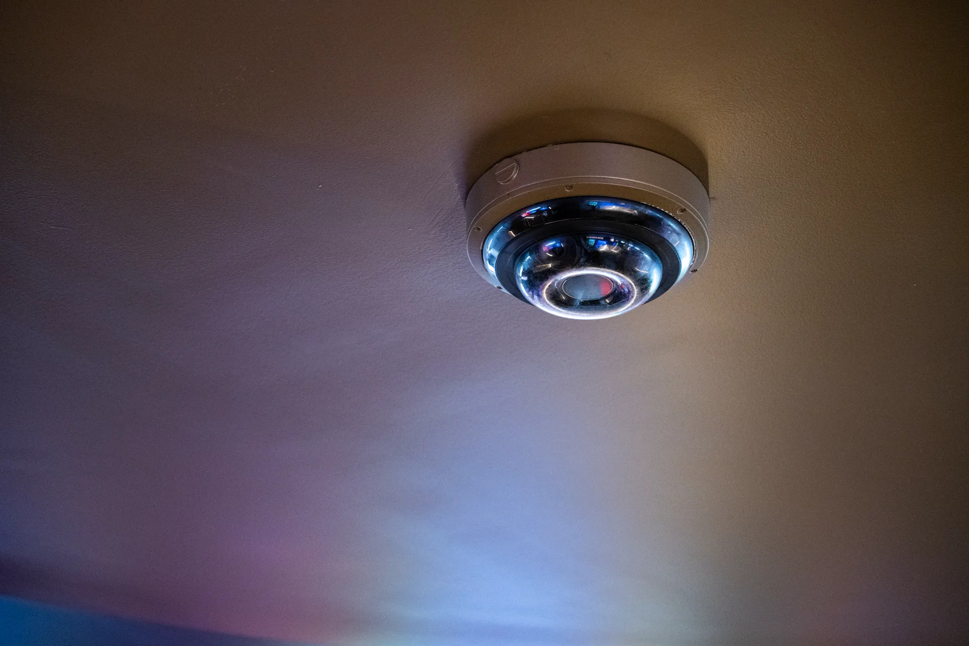 A 360 degree camera on a ceiling lit by neon light