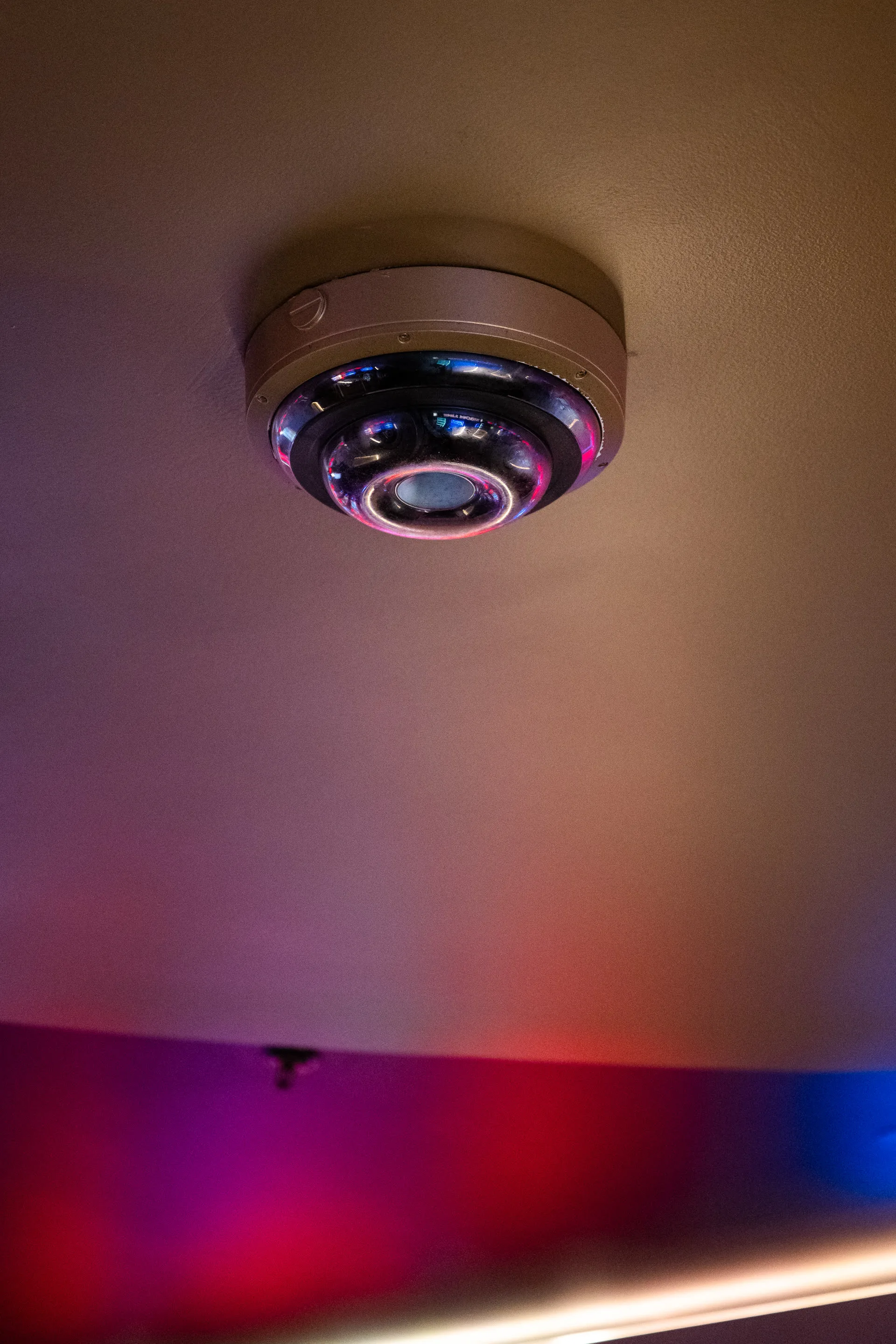 Ceiling camera glowing in a dark venue