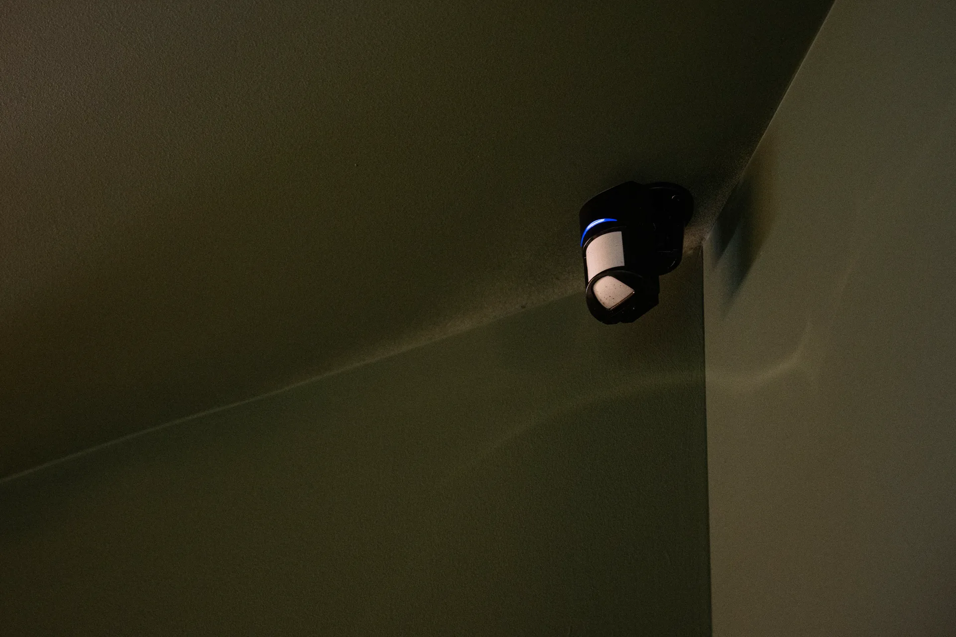 A motion detector glowing blue in a darkened room