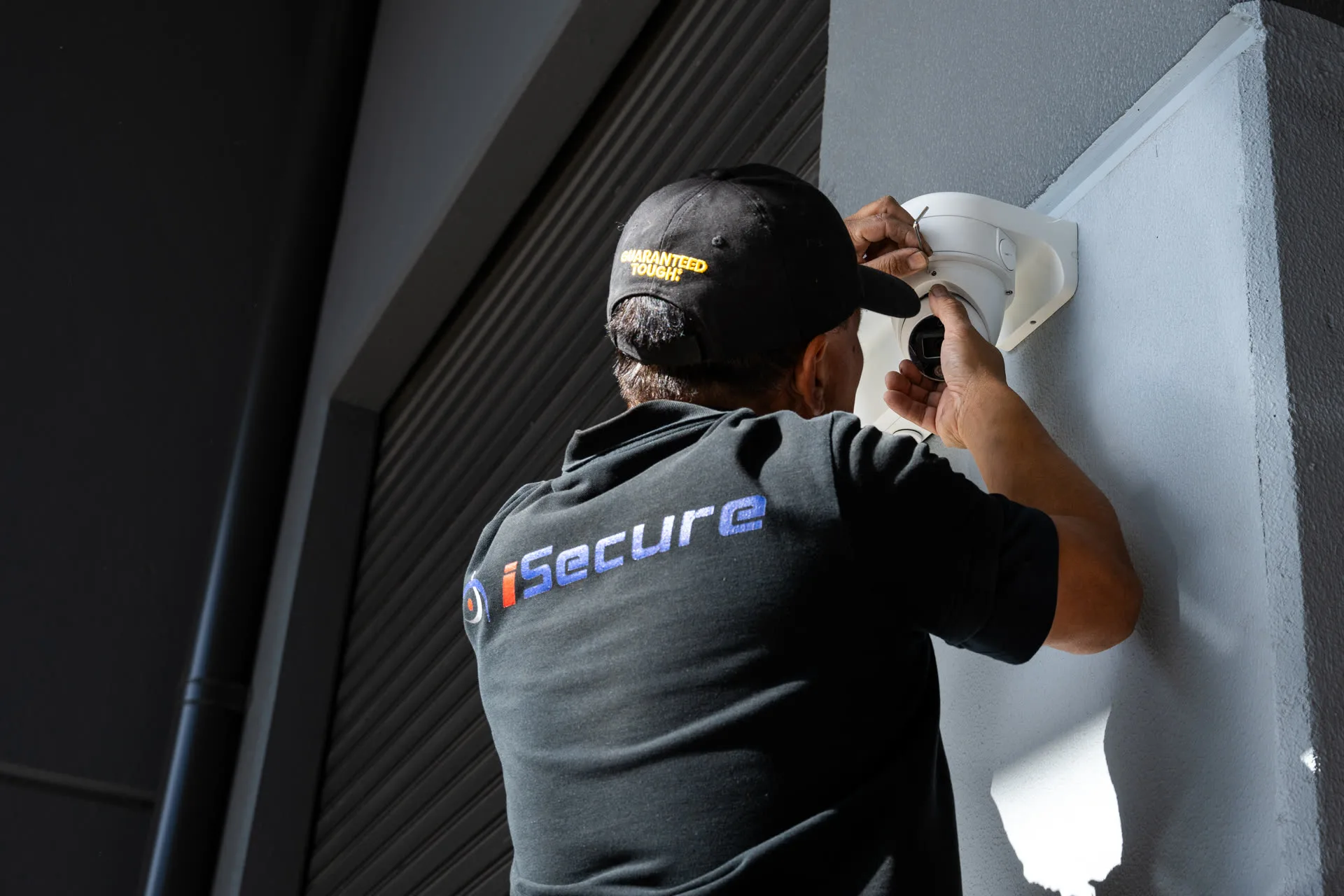 An iSecure technician installing a dome camera under an awning