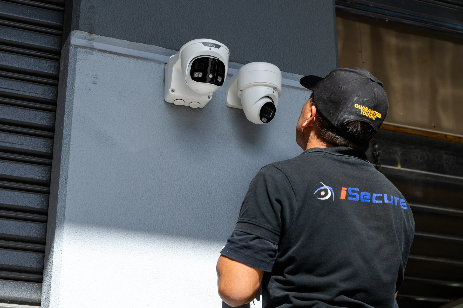 An iSecure technician inspecting cameras on a commercial wall