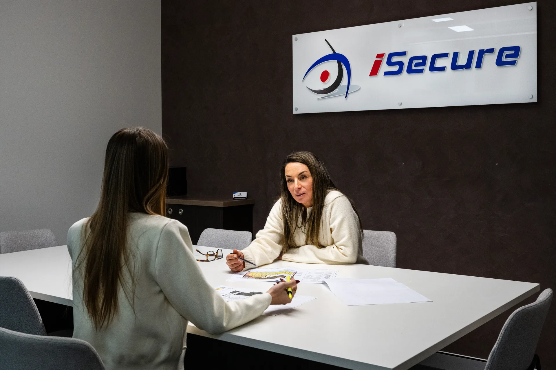 Two iSecure team members meeting beneath the iSecure sign in the Kingsgrove office